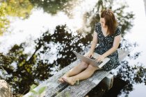Young woman using laptop on jetty, selective focus — Stock Photo