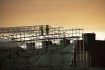 Travailleurs de la construction sur échafaudage au coucher du soleil — Photo de stock