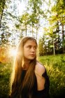 Portrait of young woman in forest at sunset — Stock Photo