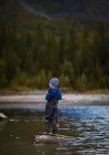 Adorable petit garçon pêchant en rivière — Photo de stock