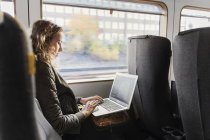 Junge Frau mit Laptop im Zug unterwegs — Stockfoto
