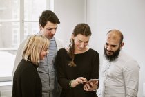 Coworkers looking at smart phone — Stock Photo