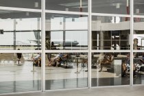 Airplane reflected in window at airport — Stock Photo