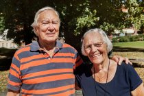 Portrait of happy senior couple standing together outdoors at sunny day — Stock Photo
