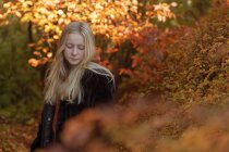 Adolescente por árboles de otoño, enfoque selectivo - foto de stock