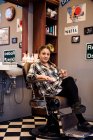 Barber sitting in chair and looking at camera — Stock Photo