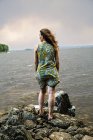Вид ззаду на жінку, що стоїть на каменях і дивиться на море — стокове фото