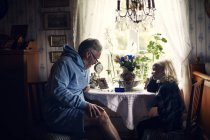 Grand-père et petite-fille à table avec des fleurs — Photo de stock
