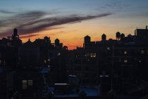 Torri d'acqua sui tetti degli appartamenti edifici al tramonto — Foto stock