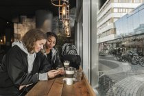 Девушка-подросток использует смартфон в кафе — стоковое фото