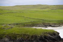 Scogliera erbosa con sagome di due persone sulle Isole Shetland, Regno Unito — Foto stock