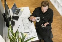 Mann benutzt Smartphone am Schreibtisch im Büro, Blickwinkel hoch — Stockfoto