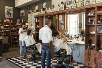 Barberes que corta el cabello de los clientes, enfoque selectivo - foto de stock