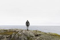 Человек ходит по скалам у озера Ваттерн в заповеднике Стора-Лунд, Швеция — стоковое фото