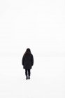 Женщина, идущая в поле зимой, вид сзади — стоковое фото