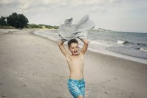 Мальчик с полотенцем на пляже, избирательный фокус — стоковое фото