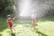 Brother and sister playing with hose, selective focus — Stock Photo