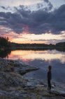 Mulher em pé junto ao Lago Landsjon ao pôr-do-sol na Suécia — Fotografia de Stock