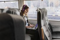 Молода жінка подорожує поїздом за допомогою ноутбука — стокове фото