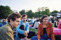 Young friends sitting together in park — Stock Photo
