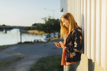 Woman using smart phone by harbour — Stock Photo