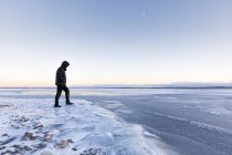 Man walking on frozen Glan lake al tramonto a Ostergotland, Svezia — Foto stock