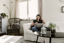 Молода жінка використовує ноутбук на дивані — стокове фото