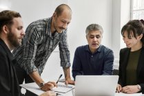 Empresarios usando laptop y trabajando juntos en la oficina - foto de stock