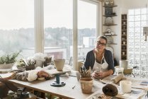 Женщина за столом в мастерской по гончарному делу, избирательный фокус — стоковое фото