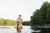 Hijo sobre los hombros del padre en el lago Kappemalagol, Suecia - foto de stock