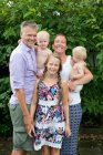 Portrait de famille heureuse avec trois enfants debout ensemble à l'extérieur et souriant à la caméra — Photo de stock