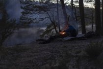 Adolescent par le feu de camp au coucher du soleil près du lac Oxsjon à Lerum, Suède — Photo de stock