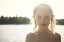 Дівчина назад освітлена сонячним промінням перед озером — стокове фото