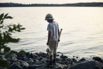 Menino segurando vara de pesca por lago — Fotografia de Stock