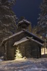 Cabane en rondins dans la neige la nuit, mise au point sélective — Photo de stock