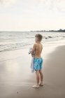 Хлопчик носить рушник на пляжі — стокове фото
