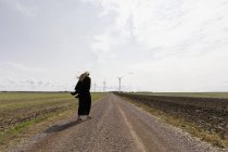 Жінка у чорній ходьбі по сільській дорозі. — стокове фото