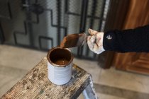 Mano del pintor sumergiendo el pincel en la lata de pintura - foto de stock
