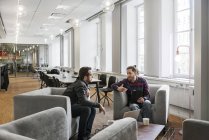 Сосредоточенные мужчины-коллеги сидят и говорят в офисе — стоковое фото