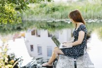 Young woman using laptop on jetty — Stock Photo