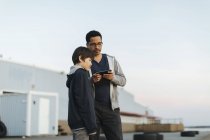 Padre e hijo usando un teléfono inteligente - foto de stock