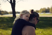 Femme adulte d'âge moyen donnant du piggyback à une fille dans un parc — Photo de stock