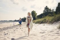 Chica llevando rocas en la playa - foto de stock