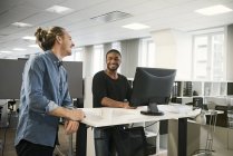 Sorrindo colegas do sexo masculino conversando na mesa no escritório — Fotografia de Stock