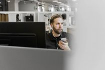 Man using smart phone at desk — Stock Photo