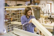 Carpenter holding timber in workshop — Stock Photo