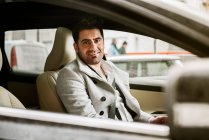 Mann sitzt im Auto und lächelt in Kamera — Stockfoto