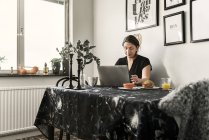 Молодая женщина с ноутбуком во время завтрака — стоковое фото