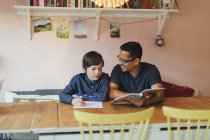 Отец помогает сыну с домашним заданием — стоковое фото