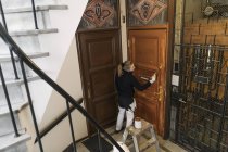 Pintor pintando puerta en edificio de apartamentos - foto de stock